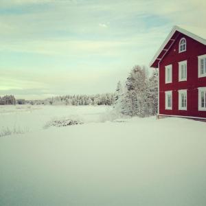 SörsjönNorrsjön的田野旁雪中的一个红色房子