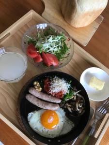 七尾Notojima Guesthouse HaNaMi的木托盘上的两盘食物,包括鸡蛋和沙拉