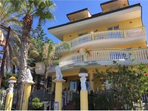 吉泽里亚克里达酒店及餐厅的带阳台和棕榈树的大型黄色房屋