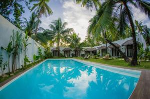 卢纳将军城帕拉卡酒店的棕榈树和小屋的度假游泳池