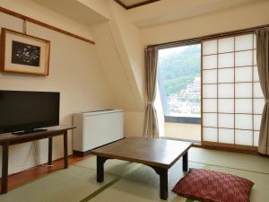 千曲市Riverside Uedakan的客厅配有电视、桌子和窗户。