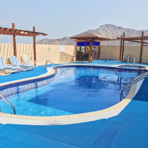 艾阿卡艾阿卡美丽华酒店的一座带椅子的大型蓝色游泳池和一座建筑
