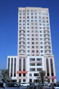 科威特贝努公寓的一座高大的白色建筑,前面有汽车停放