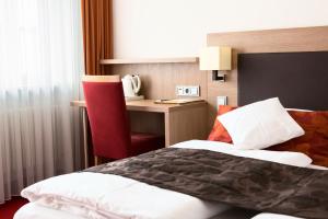 梅明根维西斯罗斯酒店的配有一张床和一张书桌的酒店客房