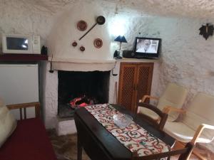 PegalajarCueva El Madrono的客厅设有壁炉、桌子和椅子