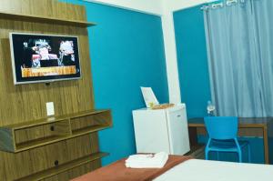马卡埃Bonjour Hotel的客房设有床、电视和蓝色的墙壁。