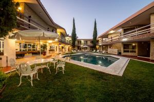 Actopan金塔里维拉酒店的后院设有游泳池、桌子和椅子