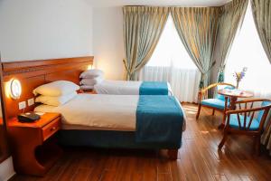 拉马拉城市客栈皇宫酒店的酒店客房带两张床和一张桌子以及椅子。