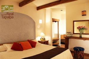 塔帕尔帕Hotel Posada Real Tapalpa的一间卧室配有一张带红色枕头的大床