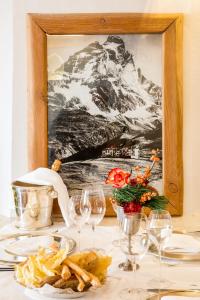 布勒伊-切尔维尼亚圣胡贝图斯度假酒店的一张桌子,上面放着酒杯,一张山的照片