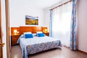 大加那利岛拉斯帕尔马斯卡萨公寓的一间卧室配有一张带蓝色枕头的床和一扇窗户。