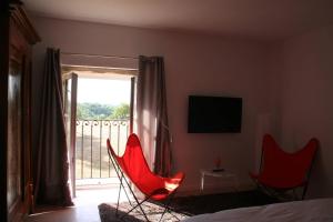 ChaponostLes terres的一间带两张红色椅子的卧室和一个阳台