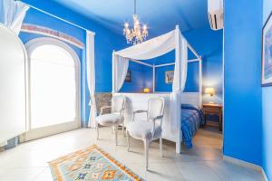 加沃拉诺La Locanda della Vecchia Hosteria的蓝色卧室配有天蓬床和椅子