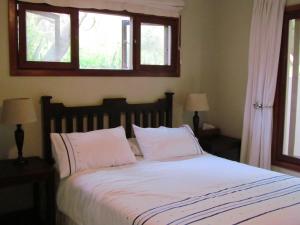 Ponta MalanganeNkumbe Bush Retreat Family Home的一间卧室配有一张带白色床单的床和两个窗户。