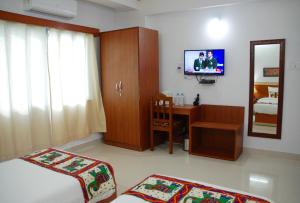 菩提伽耶菩提迦耶酒店学校的一间卧室配有一张床、一张书桌和一台电视。