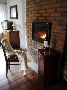 GarczChata na Zielonym Wzgórzu的客厅设有壁炉和带酒杯的椅子