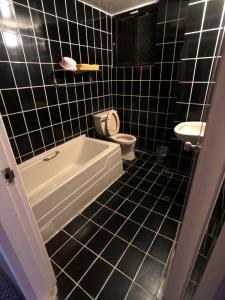 礁溪亚仕登旅馆的黑色瓷砖浴室设有浴缸和卫生间
