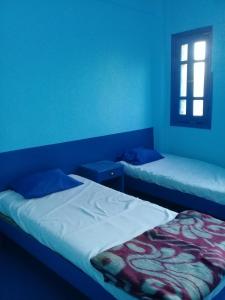 卢克索Oasis hotel的配有两张床铺的蓝色墙壁和窗户