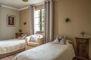 Casamaccioli卡萨万尼尔拉酒店的一间卧室设有两张床、一把椅子和一个窗户。