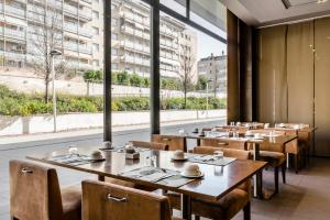 圣胡安德斯皮巴塞罗那盖特埃克酒店的餐厅设有木桌、椅子和大窗户。