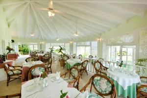 拉斯加勒拉斯塞雷纳别墅酒店的一间设有白色桌椅和窗户的用餐室