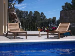 巴古尔Villa Hermosa的两把木椅,坐在游泳池旁
