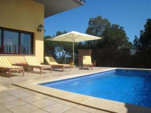 巴古尔Villa Hermosa的一个带两把椅子和遮阳伞的游泳池