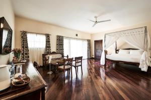 内罗毕赛法瑞公园酒店的一间卧室配有一张床铺和一张桌子,还有一间用餐室