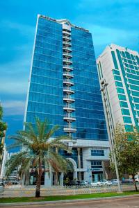 阿布扎比Platinum Hotel Apartments的一座高大的建筑,前面有一棵棕榈树