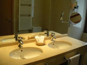 马德里马德里卡斯蒂拉斯二世酒店的浴室柜台设有两个盥洗盆和镜子