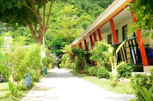 皮皮岛Chongkhao Resort- SHA Certified的一条步道,旁边是一座树木繁茂的房屋和一座建筑