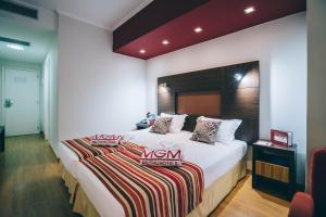 丰沙尔拉加马德拉穆图酒店的卧室配有一张带条纹毯子的大型白色床