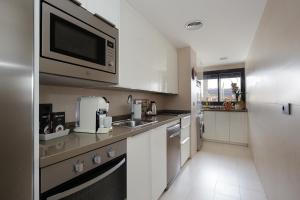 格拉纳达Atico Be suite Granada的厨房配有白色橱柜和微波炉