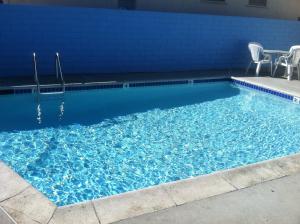 洛杉矶快乐罗杰酒店的一个带椅子和蓝色墙壁的游泳池