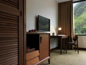 台北有诚商旅的酒店客房设有一张书桌、一台电视和一个窗户。