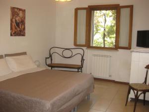 乌尔比诺Country House-B&B-Appartamenti Ai Cipressi的卧室配有床、椅子和窗户。