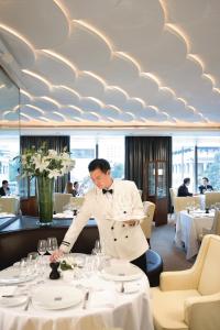 香港Mandarin Oriental, Hong Kong的站在餐厅桌子上的身着白色衣服的人