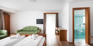 奥蒂塞伊Hotel Garni Planaces的酒店客房,设有两张床和一张绿色沙发