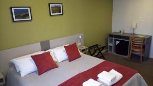 罗卡将军市Estepa Hotel的一间卧室配有一张带红色和白色枕头的大床