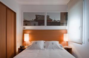 塞维利亚艾斯拉瓦公寓酒店的一间卧室配有一张带两盏灯的床和一扇窗户。