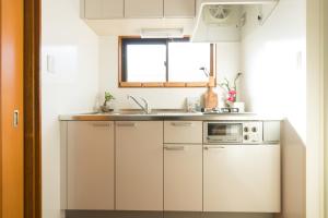东京K&K Apartment Kita-Akabane #301的厨房配有白色橱柜、水槽和窗户。