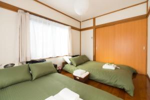 东京K&K Apartment Kita-Akabane #301的客房设有两张绿色的床和窗户。