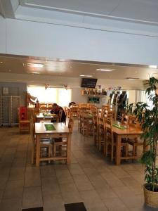 BygdeåMotell Trafikanten的一间设有木桌和椅子的餐厅,以及一位坐在