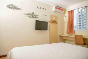 惠州7天连锁酒店惠州西湖店的卧室配有一张床,墙上配有电视。