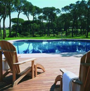 厄尔-汝姆披多努弗波提尔高尔夫酒店的一个带两把椅子的游泳池,位于木甲板旁