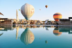 格雷梅Kelebek Special Cave Hotel & Spa的三只热气球飞越一池水