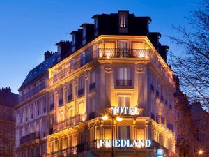 巴黎Hotel Le Friedland的一座有酒店标志的建筑在晚上被点燃