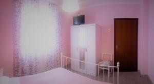 Mulazzo埃尔卡拉酒店的一间卧室设有粉红色的墙壁、一张床和橱柜