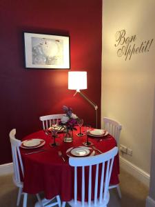 爱丁堡Hamish's Hame Edinburgh Licence No EH 69774 P的红色的餐桌,配有红色的桌布和白色的椅子