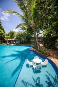 皮帕索姆布拉阿瓜富力斯卡度假酒店的一个带椅子和桌子的游泳池以及棕榈树